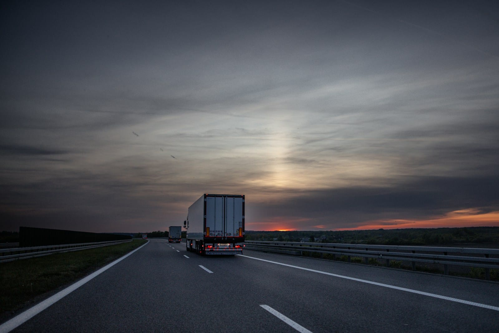 Linehaul trucks on an Australian highway at sunset — hours counted, rest windows protected